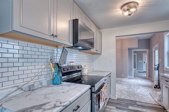 kitchen with light wood finished floors, electric range, tasteful backsplash, baseboards, and light stone countertops