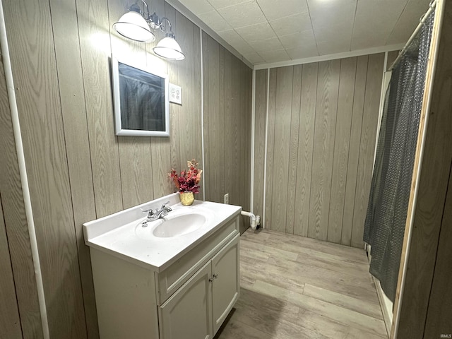 bathroom with wood finished floors, vanity, and wooden walls