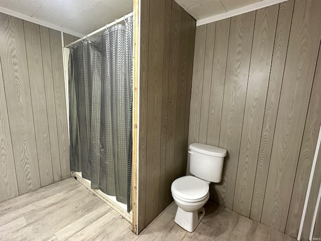 bathroom with wood walls, wood finished floors, and toilet