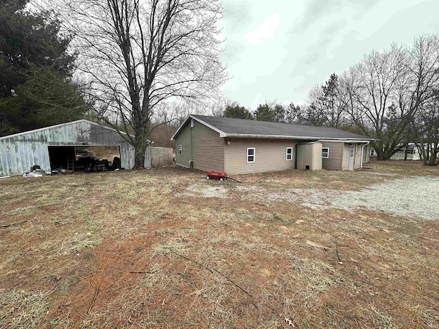 rear view of house featuring a detached garage, a pole building, and an outdoor structure