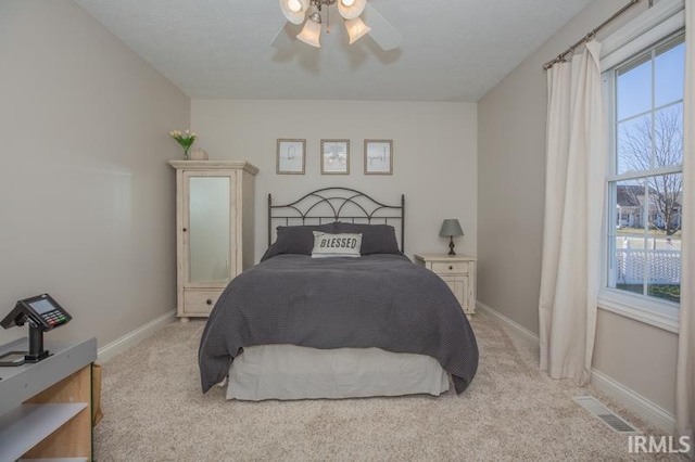 bedroom with baseboards, ceiling fan, visible vents, and light colored carpet