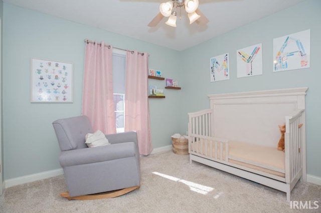 bedroom with a nursery area, carpet, baseboards, and a ceiling fan