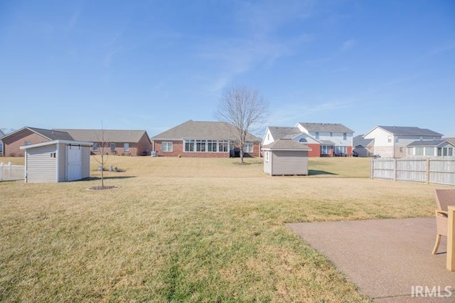 view of yard featuring a residential view, an outdoor structure, fence, and a shed