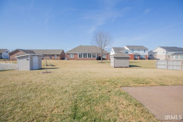 view of yard with a residential view, an outdoor structure, fence, and a storage unit