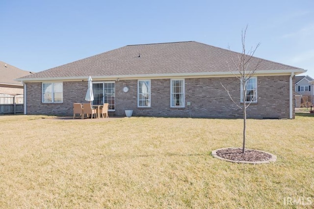 rear view of property with brick siding, a lawn, and a shingled roof