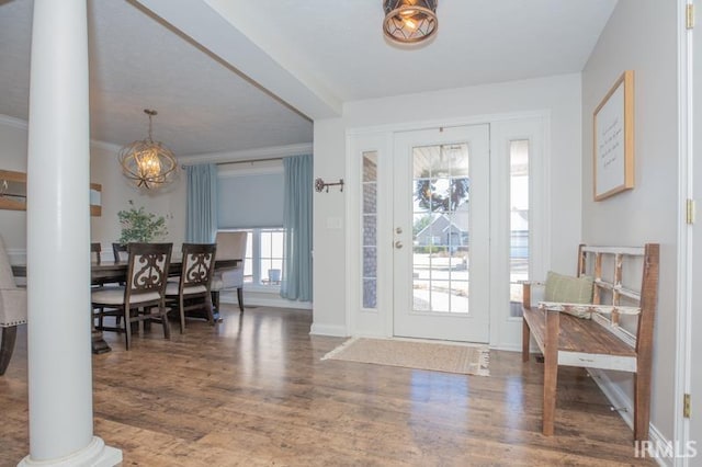 foyer with crown molding, dark wood finished floors, decorative columns, and baseboards