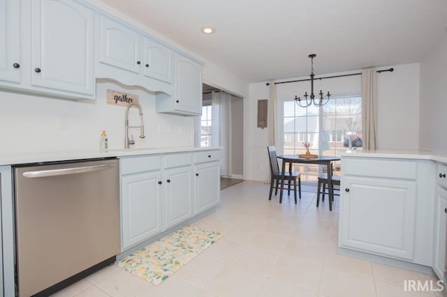 kitchen featuring white cabinets, light countertops, stainless steel dishwasher, plenty of natural light, and decorative light fixtures