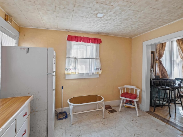 kitchen featuring freestanding refrigerator, white cabinets, light countertops, and baseboards