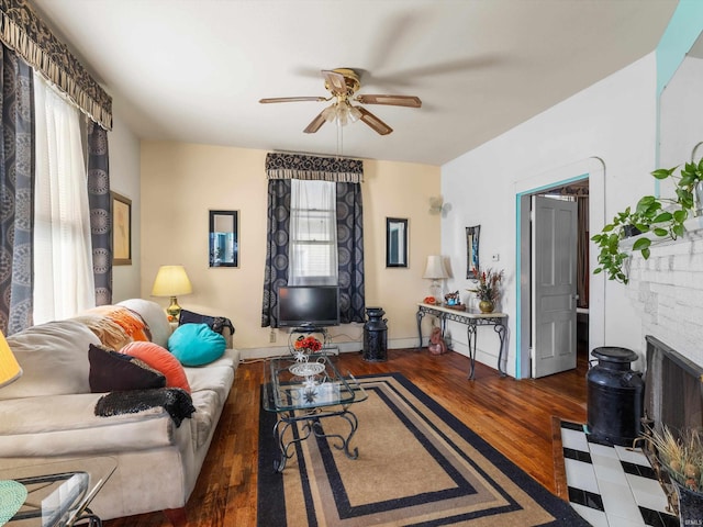 living room featuring a fireplace with flush hearth, ceiling fan, and dark wood-type flooring