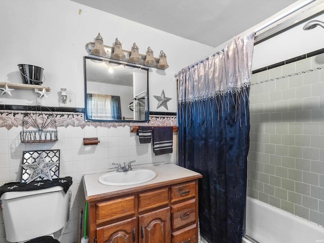 full bath featuring toilet, a wainscoted wall, shower / bath combo with shower curtain, vanity, and tile walls