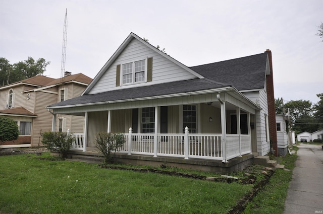 farmhouse-style home with covered porch, roof with shingles, and a front lawn