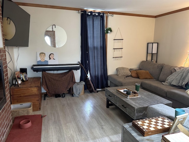 living area with a brick fireplace, ornamental molding, and wood finished floors