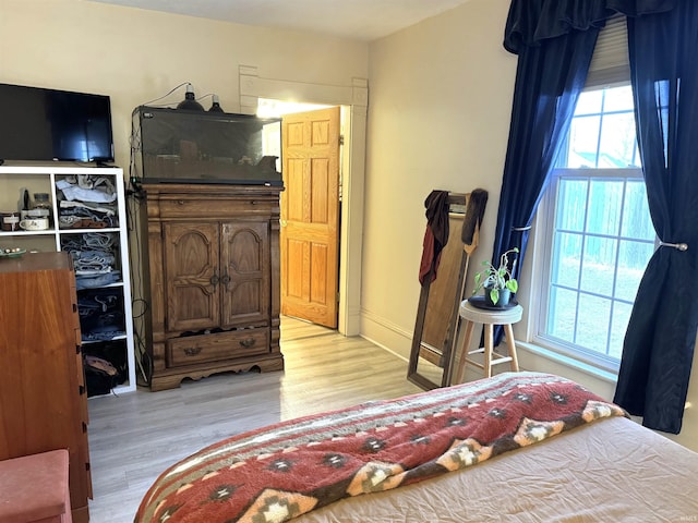 bedroom with multiple windows and light wood-style floors