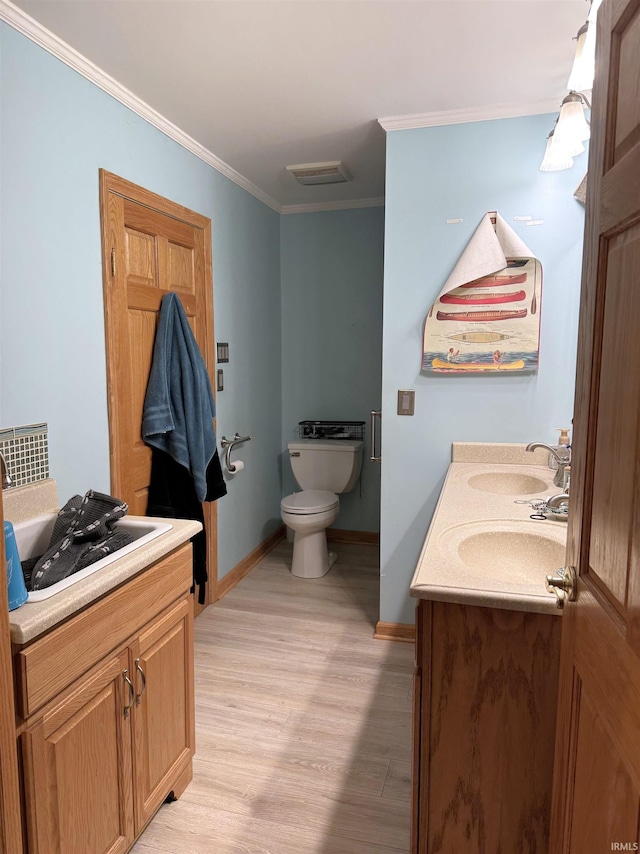 bathroom featuring crown molding, a sink, toilet, and double vanity