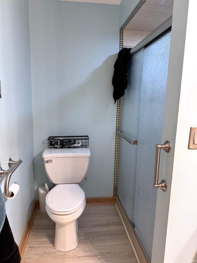 full bathroom featuring toilet, a shower stall, and wood finished floors