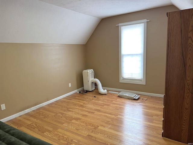 bonus room featuring light wood-type flooring, baseboards, vaulted ceiling, and a textured ceiling