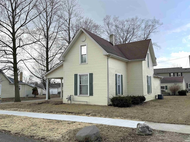 view of front of house with a shingled roof, a chimney, and central air condition unit