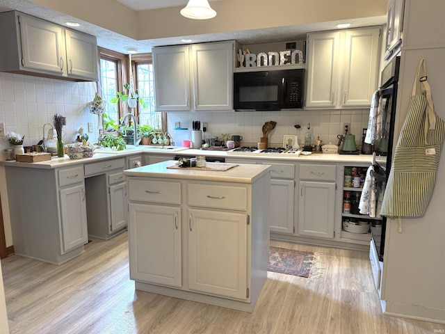 kitchen with white gas cooktop, black microwave, light wood finished floors, and open shelves