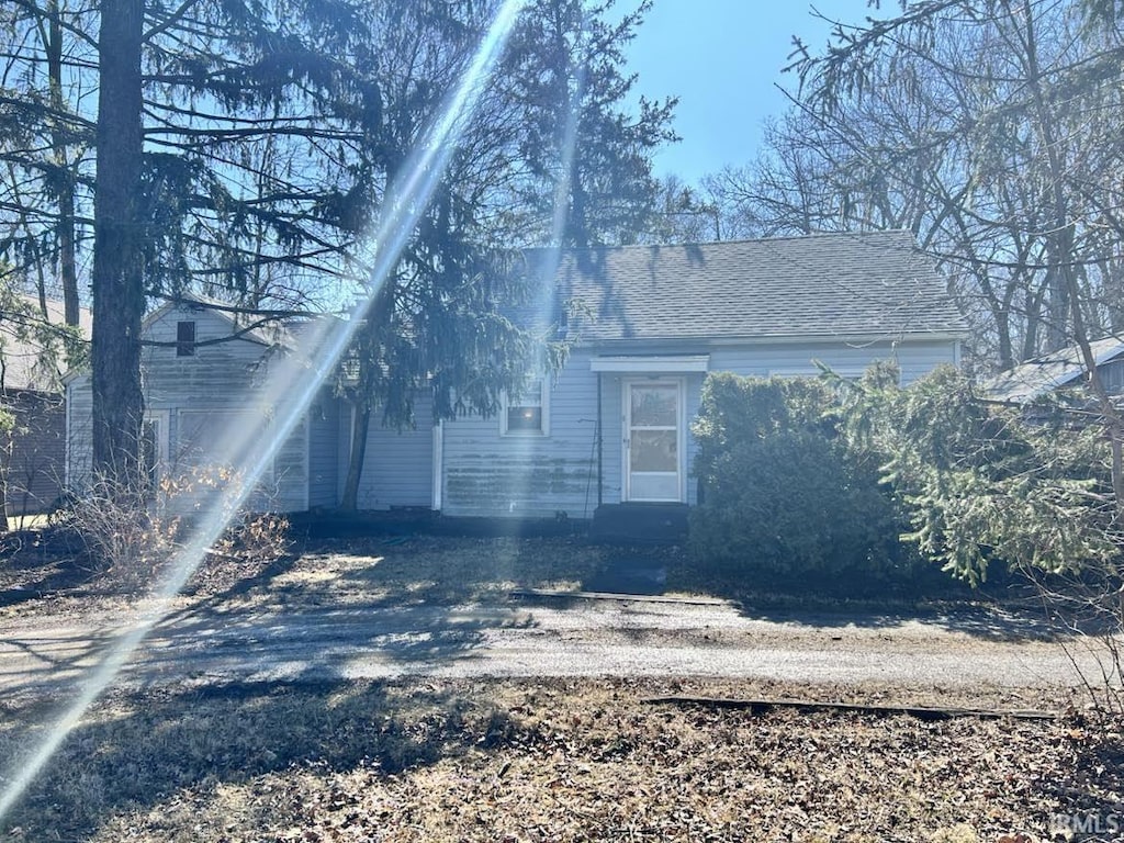 view of home's exterior with roof with shingles and dirt driveway