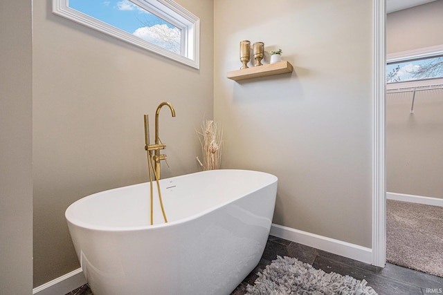 bathroom featuring baseboards and a freestanding bath