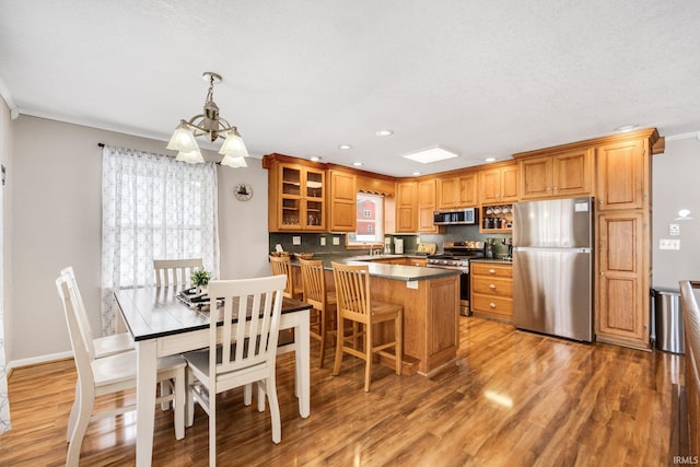 kitchen featuring stainless steel appliances, brown cabinetry, and light wood-style floors