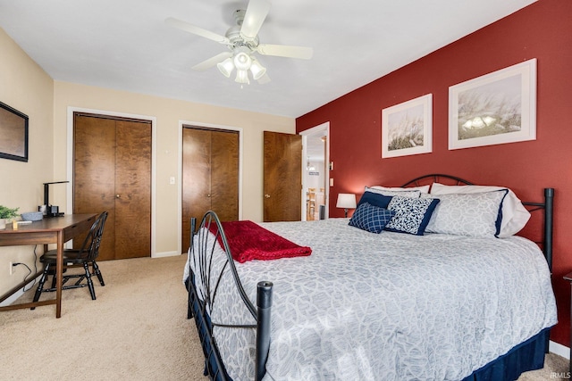 bedroom with ceiling fan, baseboards, two closets, and light colored carpet