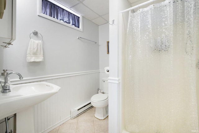 bathroom with a wainscoted wall, a baseboard radiator, curtained shower, tile patterned flooring, and a paneled ceiling