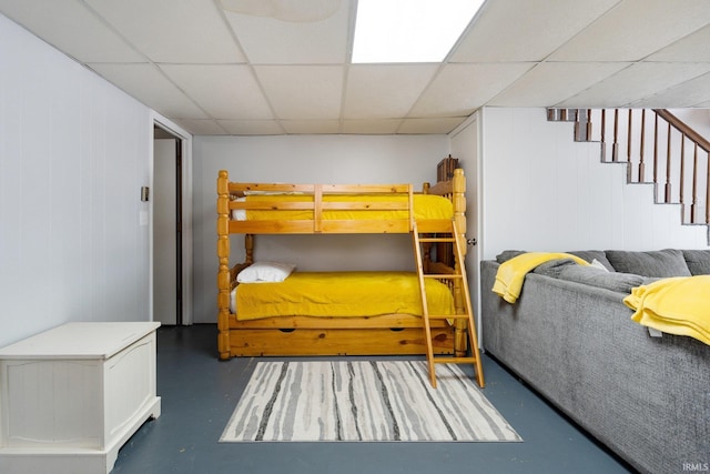 bedroom featuring finished concrete floors and a paneled ceiling