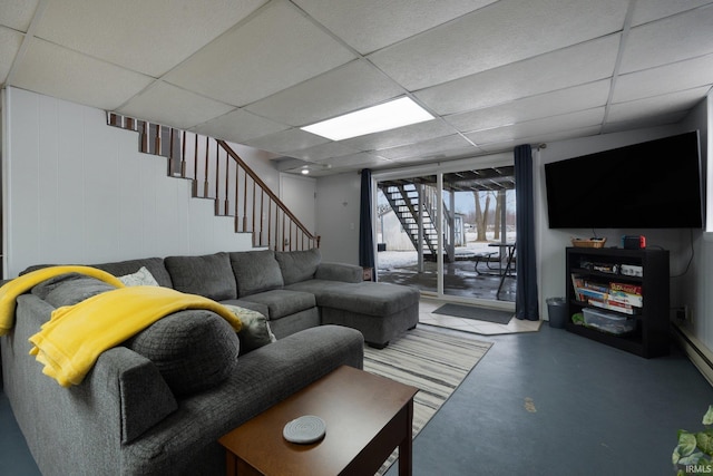 living room featuring a paneled ceiling, finished concrete floors, and stairway