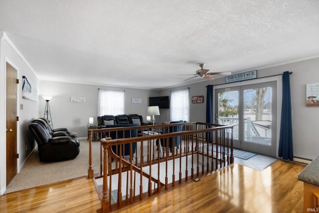 interior space with baseboards, a baseboard radiator, ornamental molding, a textured ceiling, and light wood-style floors