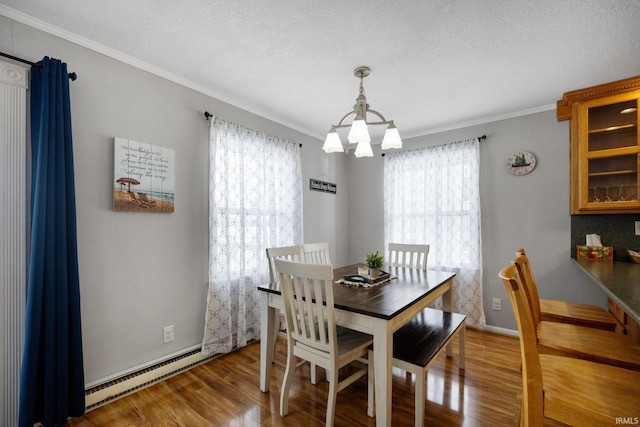 dining area featuring a baseboard heating unit, baseboards, ornamental molding, light wood finished floors, and an inviting chandelier