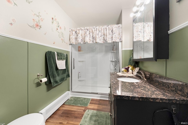 bathroom featuring toilet, wood finished floors, a shower stall, and vanity