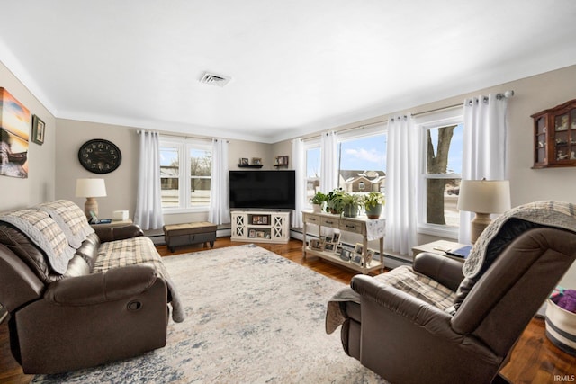 living room featuring a baseboard radiator, plenty of natural light, wood finished floors, and visible vents