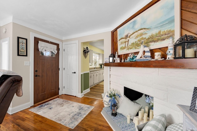 entryway featuring a fireplace, baseboards, and wood finished floors