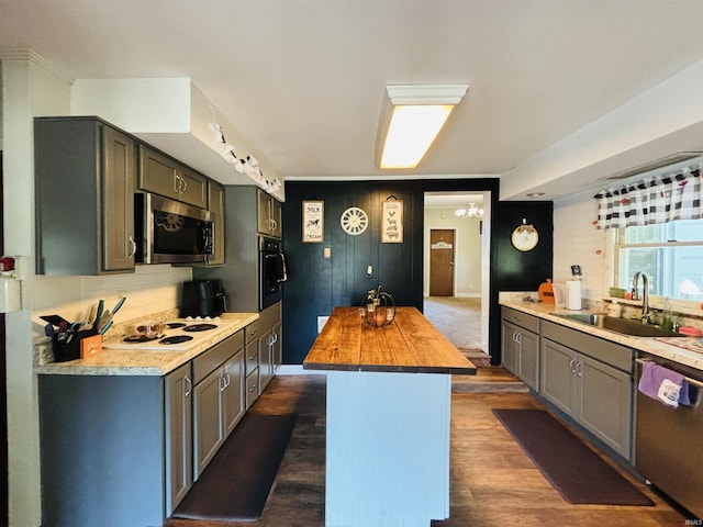 kitchen with stainless steel appliances, butcher block counters, a sink, a center island, and dark wood-style floors