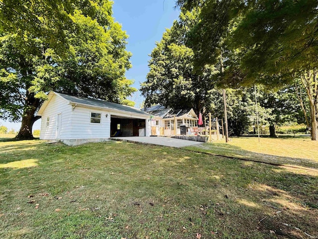 view of yard featuring a garage, a patio, and an outbuilding