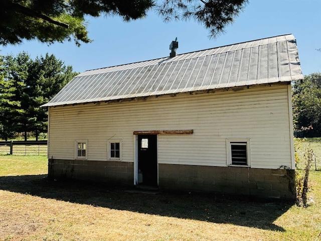 exterior space featuring fence, metal roof, and a lawn