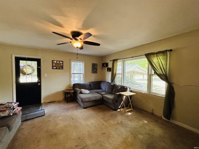 living room with ceiling fan, a textured ceiling, and light colored carpet