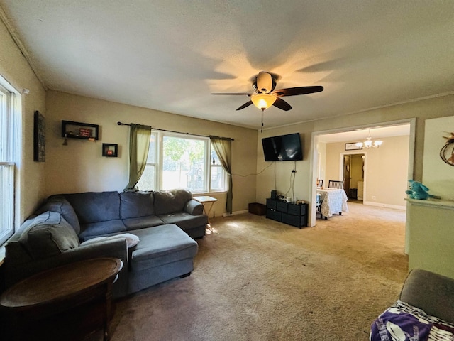 carpeted living area with ceiling fan with notable chandelier