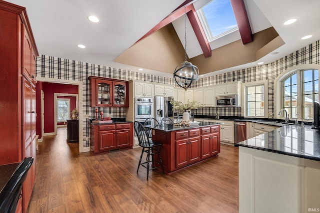 kitchen with wallpapered walls, appliances with stainless steel finishes, dark wood-style flooring, and a sink