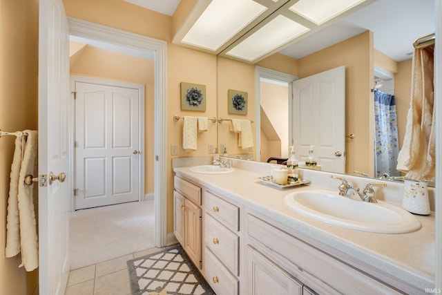 bathroom with baseboards, double vanity, a sink, and tile patterned floors