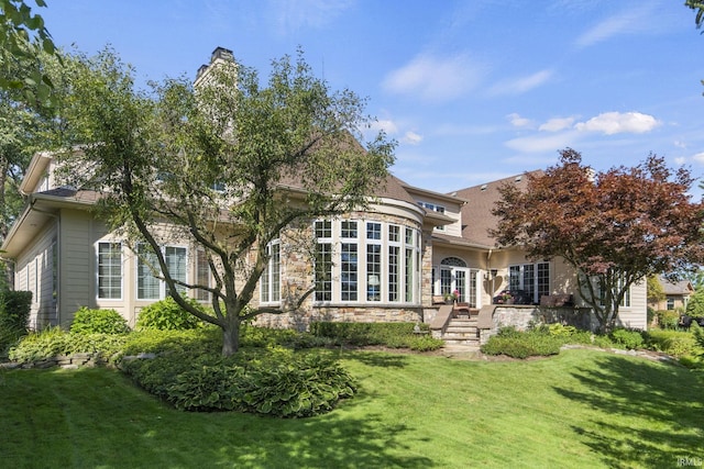 back of property featuring a yard, stone siding, and french doors