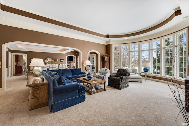 carpeted living area with arched walkways, crown molding, a tray ceiling, and recessed lighting