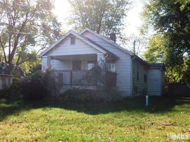 bungalow-style house featuring a front yard, covered porch, and a chimney