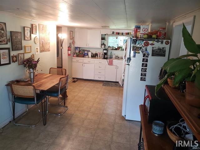 kitchen featuring light countertops, freestanding refrigerator, white cabinets, and light floors