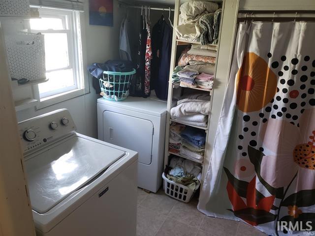 clothes washing area with laundry area, washer and clothes dryer, and light tile patterned flooring