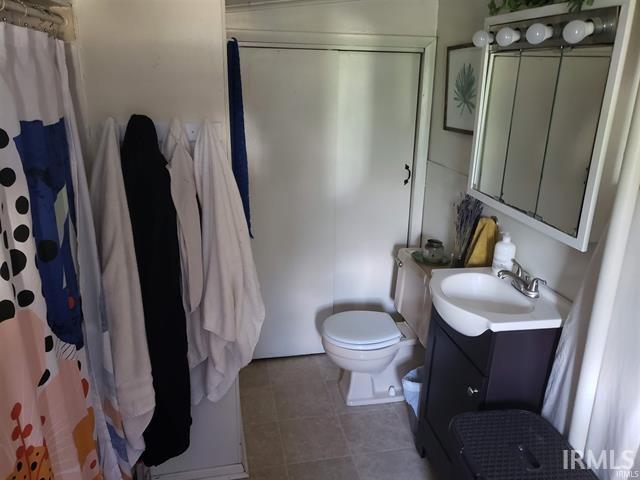 full bath featuring toilet, a shower with curtain, vanity, and tile patterned floors