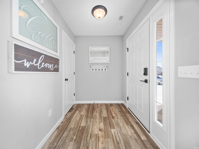 doorway with baseboards and wood finished floors