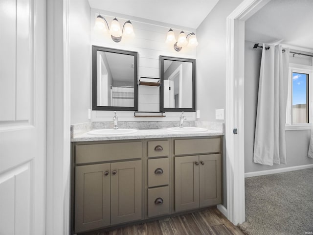 full bath with double vanity, a sink, and wood finished floors