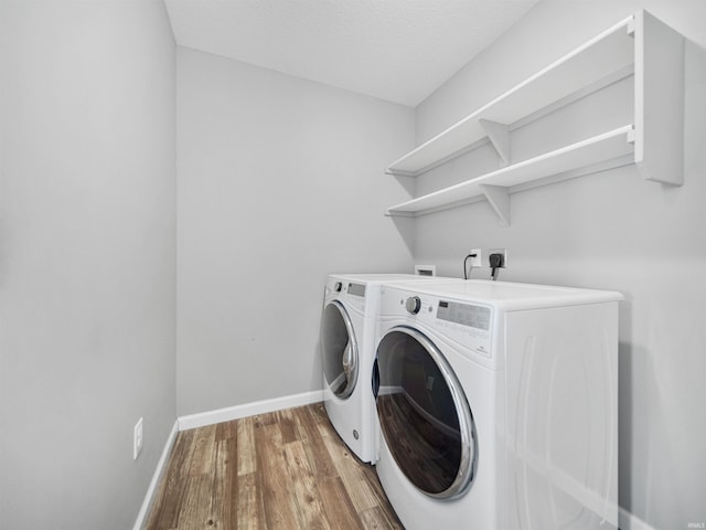 laundry room featuring laundry area, light wood finished floors, baseboards, and separate washer and dryer